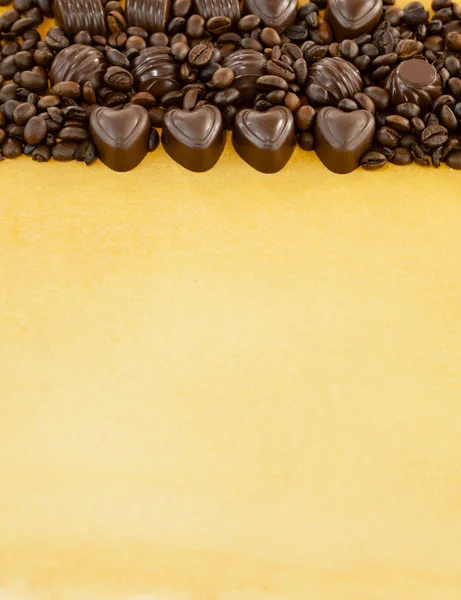 Doces de chocolate em forma de coração e grãos de café — Fotografia de Stock