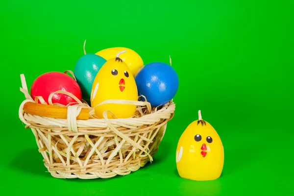 Koš s velikonoční vajíčka a žluté kuře svíčka — Stock fotografie