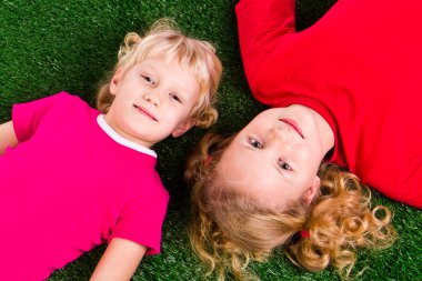 Group of happy children lying on a green grass clipart