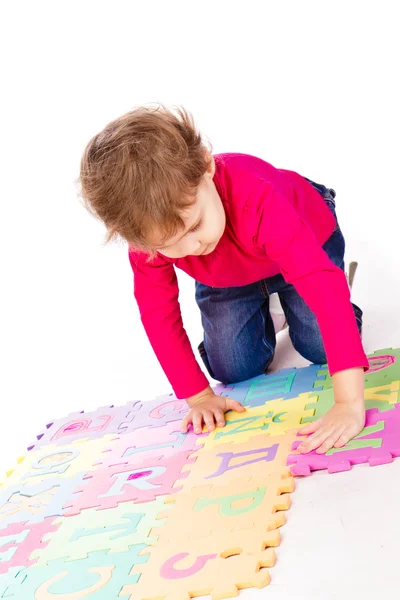 Kleines süßes Mädchen beim Lösen von Alphabet-Puzzle — Stockfoto