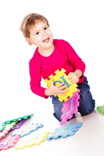 Маленькая милая девочка, решающая алфавитную головоломку — стоковое фото