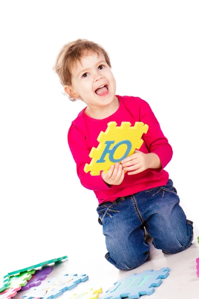 Маленькая милая девочка, решающая алфавитную головоломку — стоковое фото