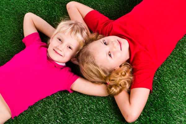 Grupo de niños felices acostados en una hierba verde —  Fotos de Stock