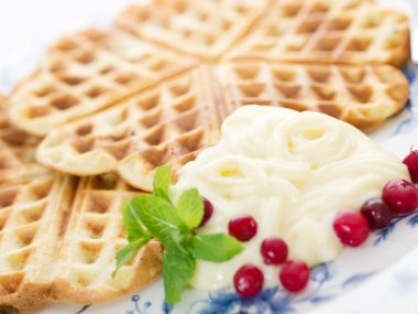 Sweet wafer hearts on dish with cream, berries and mint clipart