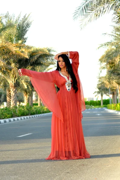 Wanita muda cantik dengan gaun merah berpose di jalan. — Stok Foto