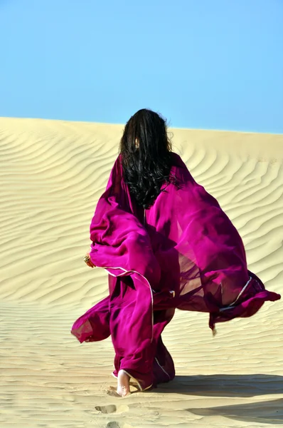 阿拉伯文深色头发的女人穿越沙漠 图库图片