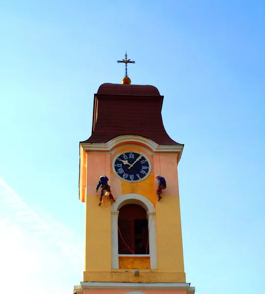 La torre de la iglesia con un reloj y que pintan —  Fotos de Stock