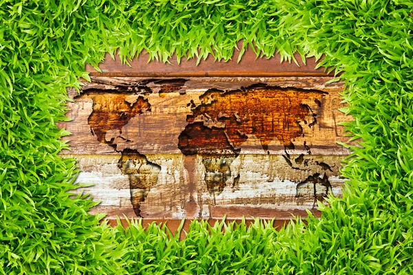 Zelené trávy a mapa světa na texturu dřeva — Stock fotografie