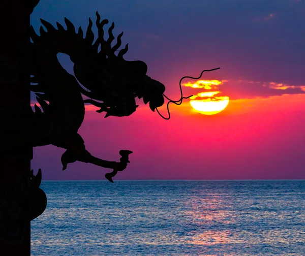 Dragon silhouet en zonsondergang in de zee — Stockfoto