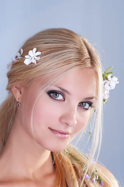 Portrait de femme blonde souriante avec des fleurs dans les cheveux Image En Vente