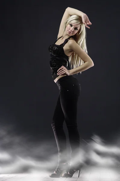 Femme blonde blanche en posture pleine longueur, vêtue de noir sur un bac foncé Images De Stock Libres De Droits