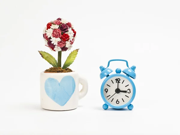Blue alarm clock with cup of rose flower — Stock Photo, Image