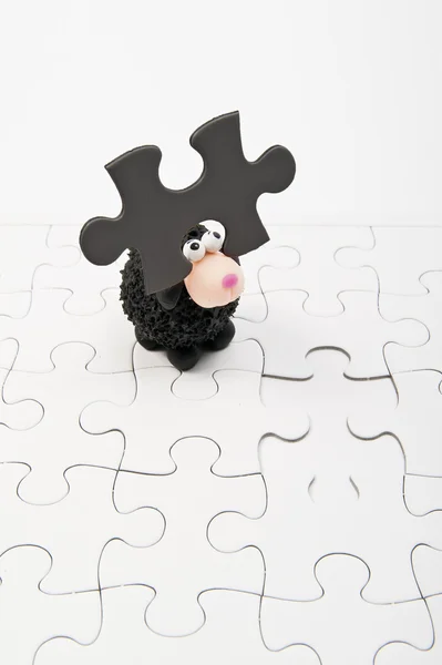 Black sheep with one dark gray jigsaw on head — Stock Photo, Image