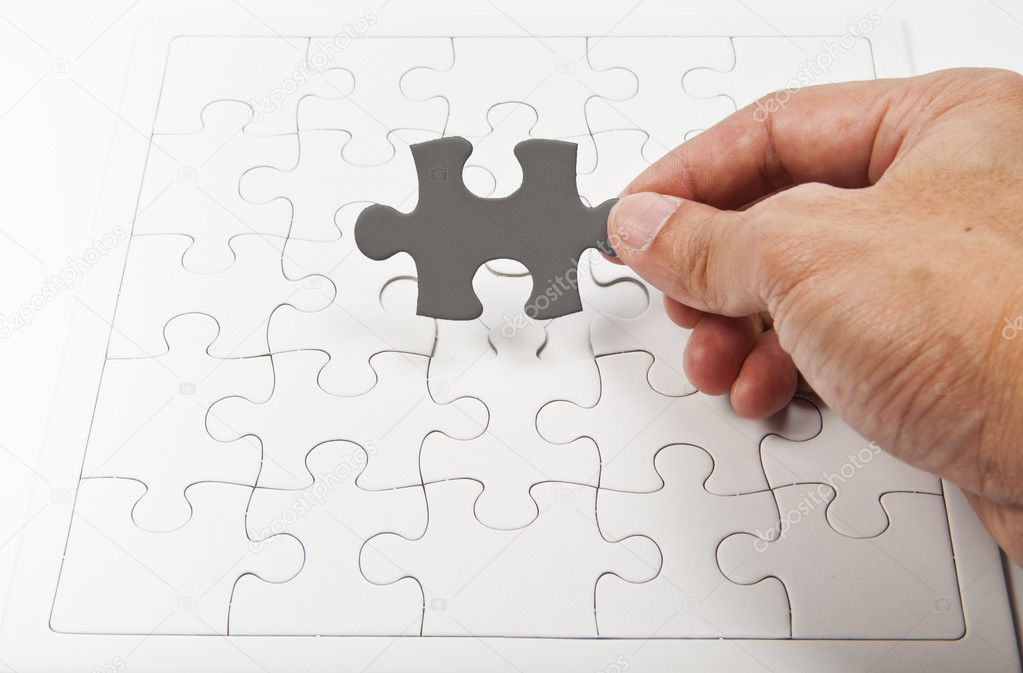Holding one gray jigsaw in one hand