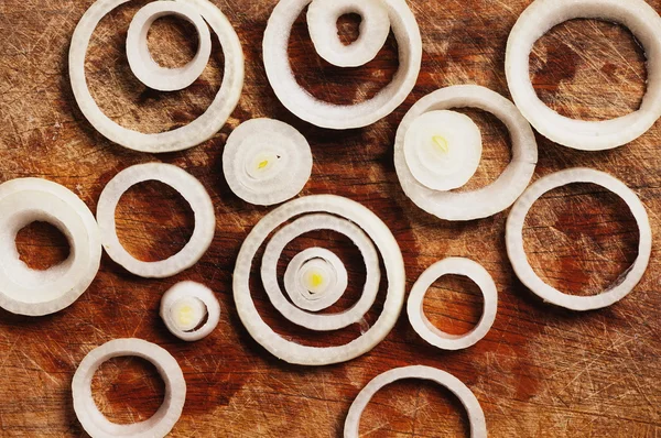 Cibulové kroužky na dřevěné pozadí — Stock fotografie