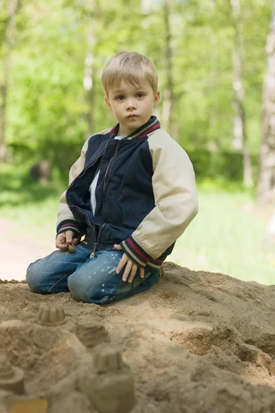 Um menino constrói um castelo de areia . — Fotografia de Stock