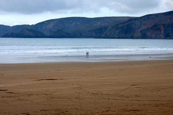 Casal anônimo em silouhette andando na praia — Fotografia de Stock