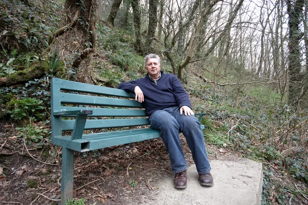 Зрелый мужчина сидит на скамейке — стоковое фото
