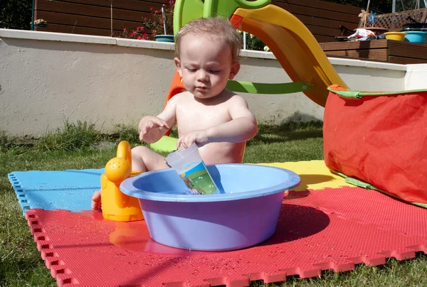 Ребенок играет с водой в саду — стоковое фото