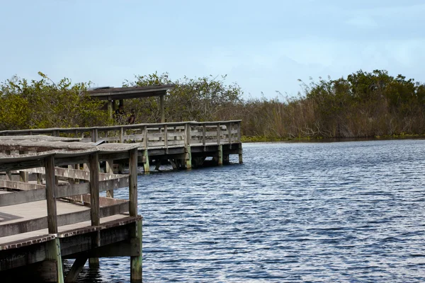 Anônimo de pé em uma ponte de madeira sobre um lago — Fotografia de Stock