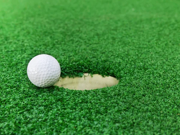 Мяч для гольфа возле лунки — стоковое фото