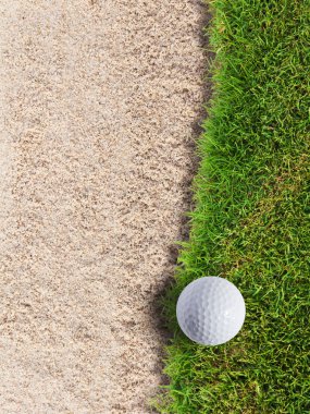 Golf ball on green grass near sand bunker clipart