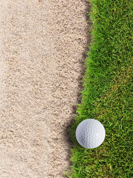 Мяч для гольфа на зеленой траве возле песчаного бункера — стоковое фото