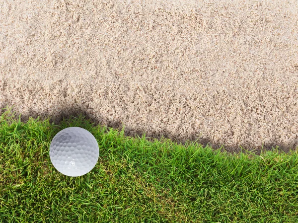 砂のバンカーの近くの緑の草にゴルフ ・ ボール — ストック写真