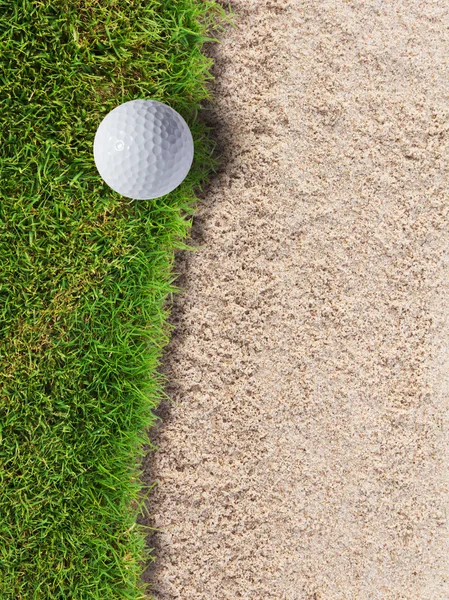 Мяч для гольфа на зеленой траве возле песчаного бункера — стоковое фото