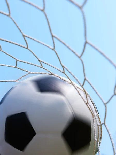 Fodbold spinning i mål mod blå himmel - Stock-foto