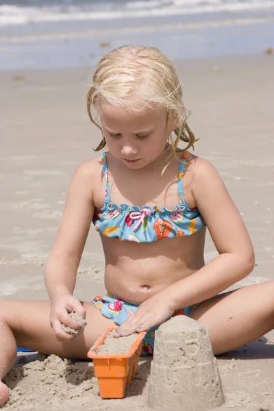 Meisje maken zandkastelen op strand — Stockfoto