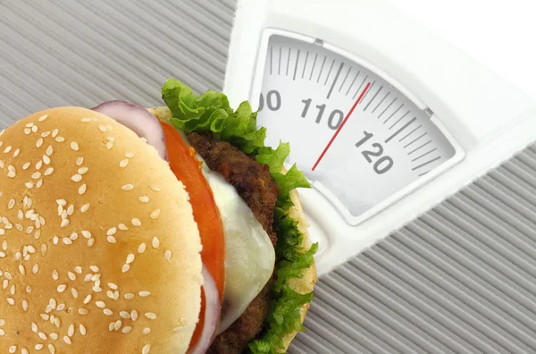 Burger on a weight scale — Stock Photo, Image