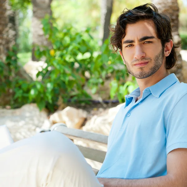 Porträt eines jungen Mannes mit Laptop im Freien auf einer Bank sitzend — Stockfoto