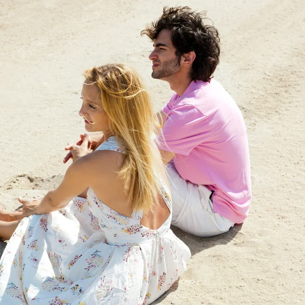 Retrato de pareja joven sentados juntos en la arena en la playa y l —  Fotos de Stock