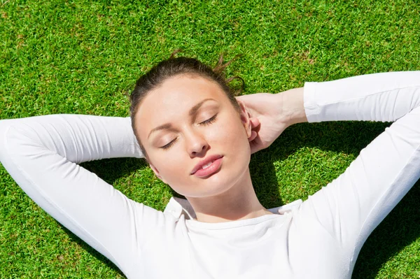 目を閉じて草の上の若い美しい女性 — ストック写真