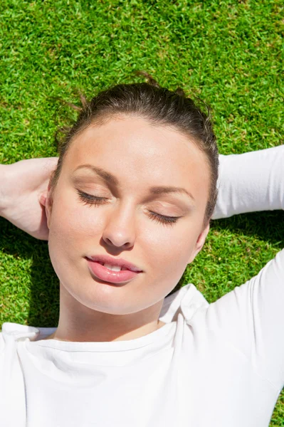 Jonge mooie vrouw op het gras met gesloten ogen — Stockfoto