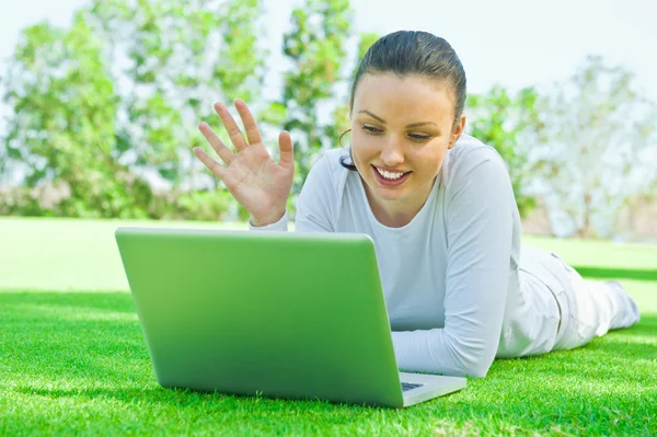 Retrato de una mujer sonriente charlando con sus amigos o familiares usando un portátil con conexión inalámbrica a Internet —  Fotos de Stock