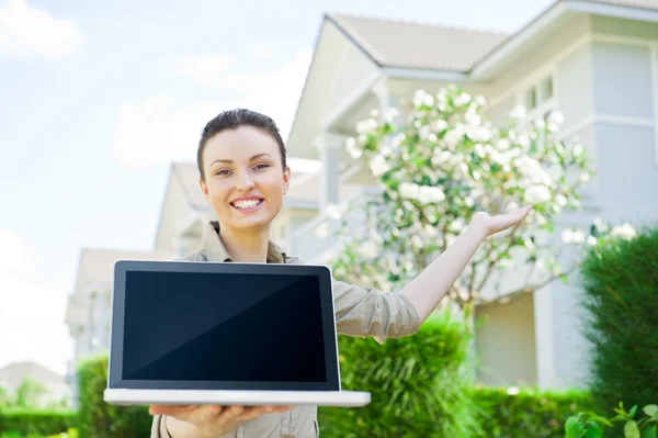 Giovane agente immobiliare bella donna con computer portatile che presenta bella casa indipendente Immagini Stock Royalty Free