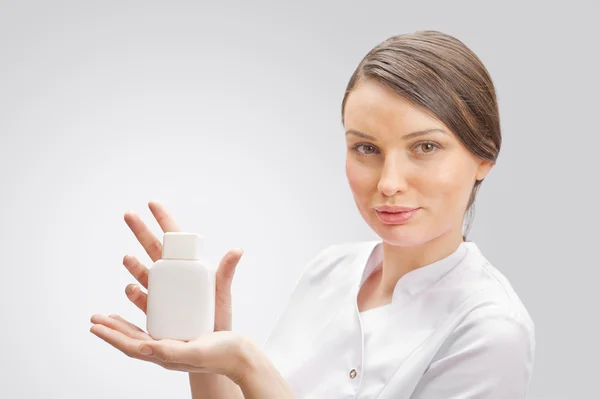 Retrato de uma mulher bonita médico apresentando novo medicamento em garrafa branca em branco . — Fotografia de Stock