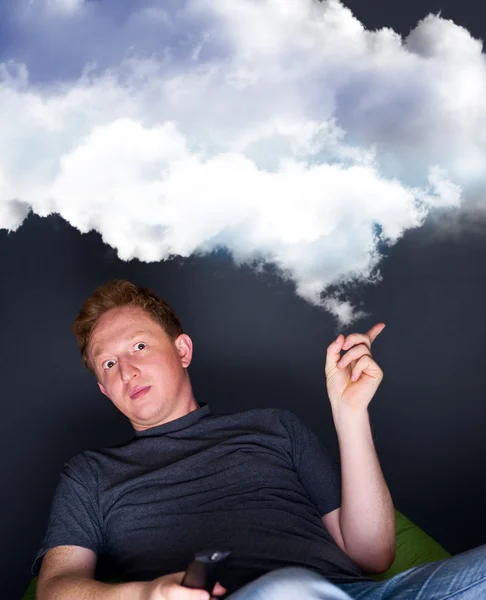 Portrait of a young man watching TV alone with a remote control and dreaming — Stock Photo, Image