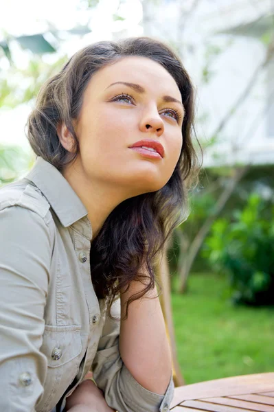 Portret słodki młoda kobieta siedzi na zewnątrz, w podwórzu domu i uśmiechając się — Zdjęcie stockowe