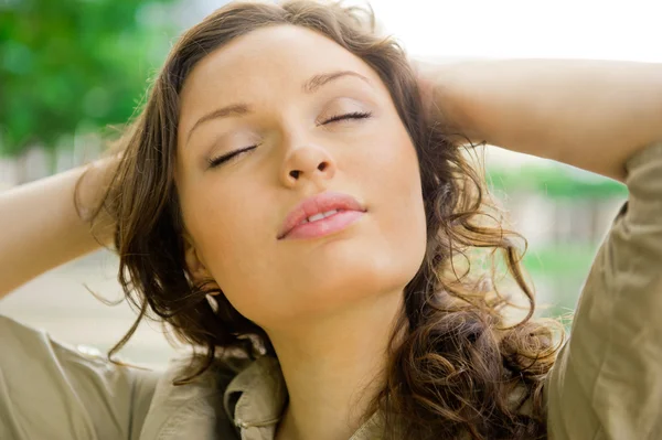 Porträtt av en sexig ung femalewith stängda ögon leende och andas frisk luft på morgonen i en park - utomhus — Stockfoto