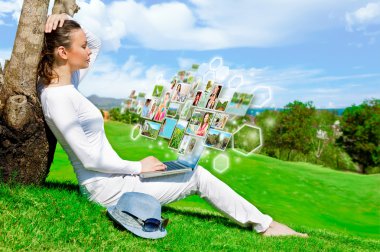 Pretty woman sitting by tree with laptop computer clipart