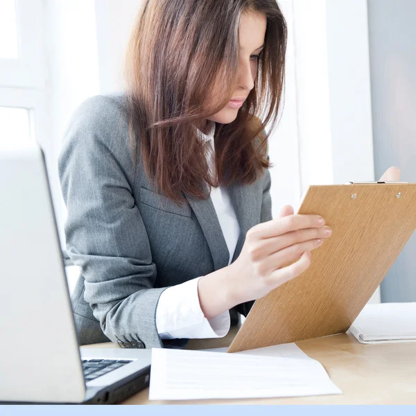 Biznes kobieta patrząc w papiery ona trzyma w jej ar — Zdjęcie stockowe