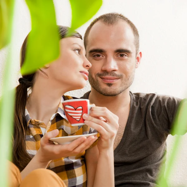 Aantrekkelijke jonge volwassen paar zitten dicht op hardhouten vloer in — Stockfoto