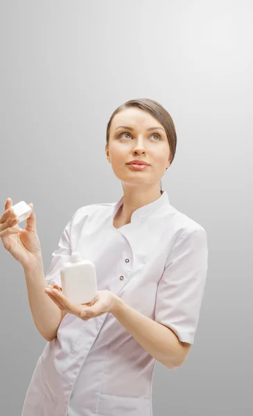 Porträtt av en vacker kvinna läkare presenterar ny medicin i blank vit flaska. — Stockfoto