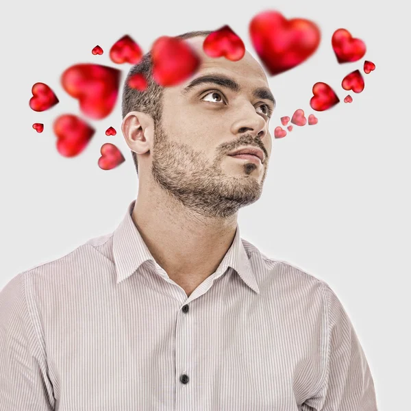 Young man thinking about love. Red hearts are flying around his — Stock Photo, Image