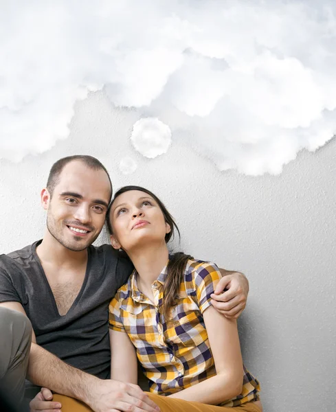 Attractive young adult couple sitting close on floor in home smi — Stock Photo, Image