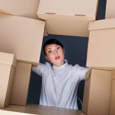 Portrait of young woman surrounded by lots of boxes. Lots of wor clipart