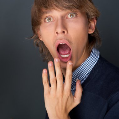 Portrait of young man with boxes against grey wall. He is afraid clipart